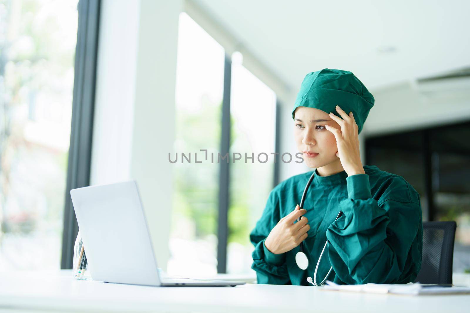 doctor using a computer and showing anxiety over patient information by Manastrong