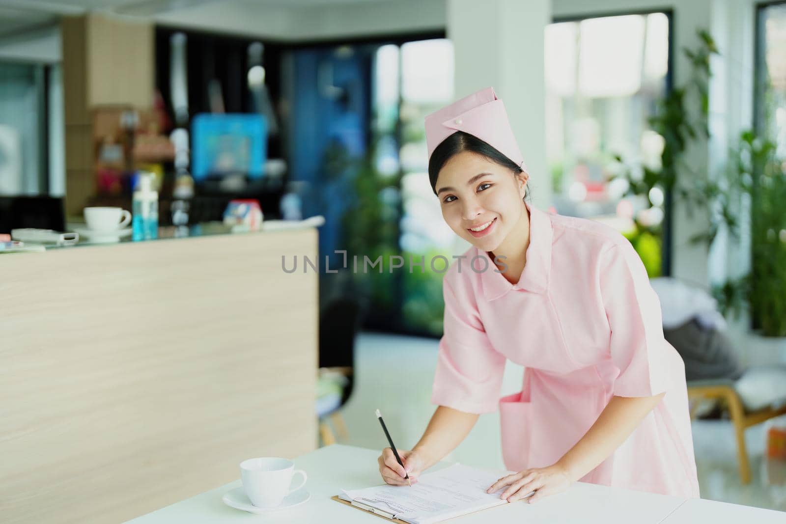 Portrait of a young Asian nurse looking at patient documents by Manastrong