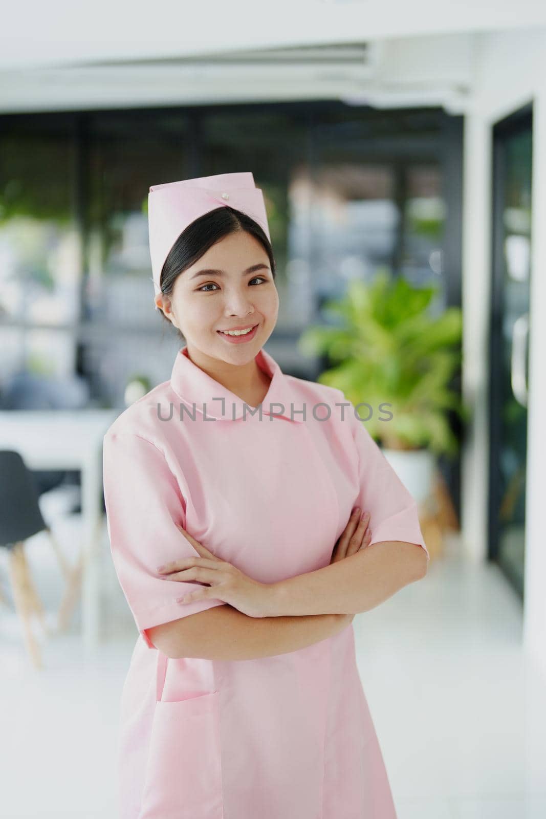 Portrait of a young nurse in a pink dress smiling happily by Manastrong