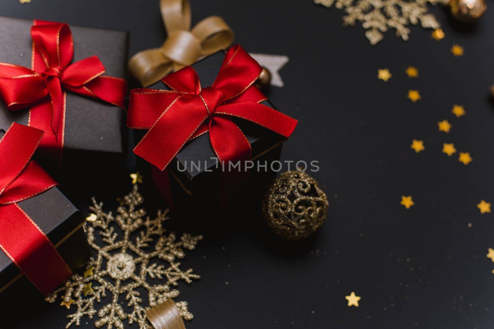 Beautiful Christmas golden snowflakes with gifts on a dark black background. Flat lay. Copy space