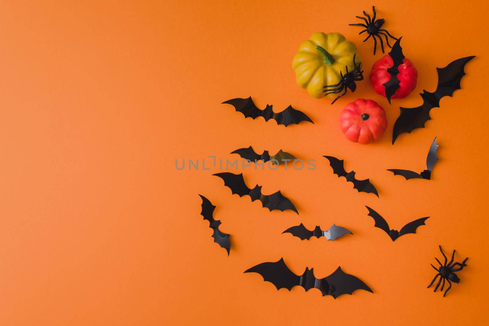 Happy halloween holiday. Halloween decorations, bats, spiders, pumpkins on an orange background. Flat lay, top view.