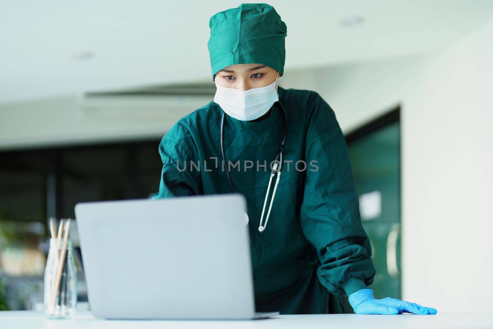 Asian doctor using a computer to look at patient information. by Manastrong