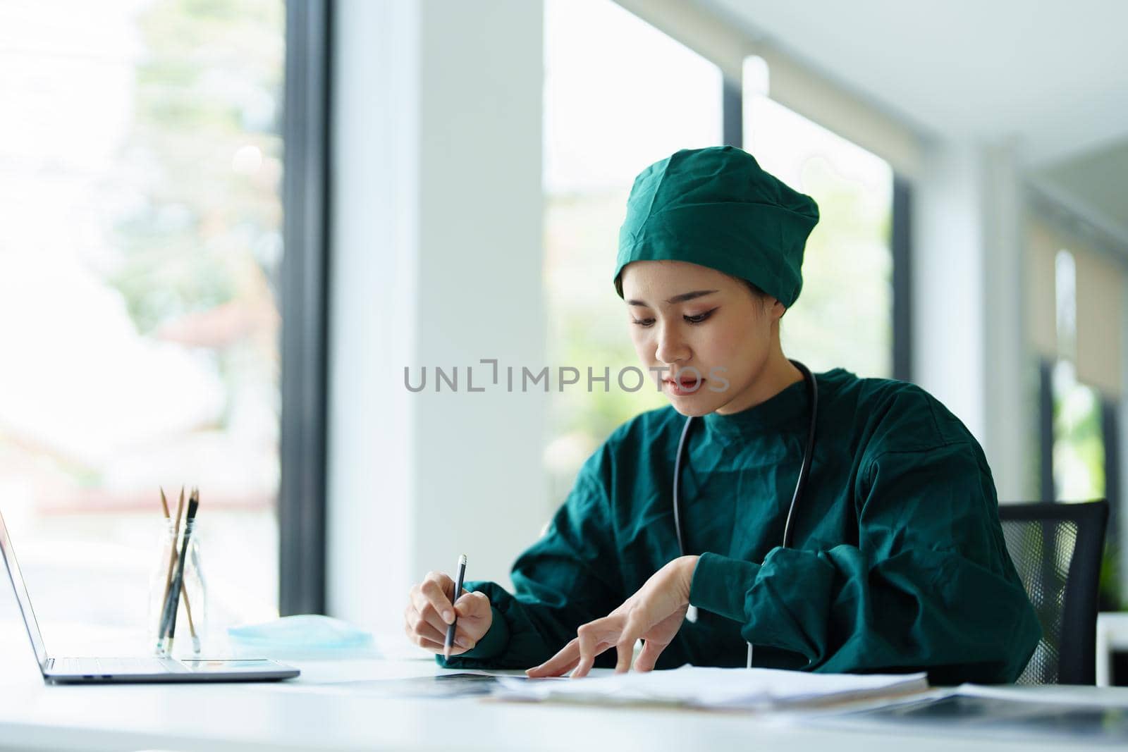 Portrait of an Asian doctor looking at patient X-ray film to analyze the abnormality of the client's body.