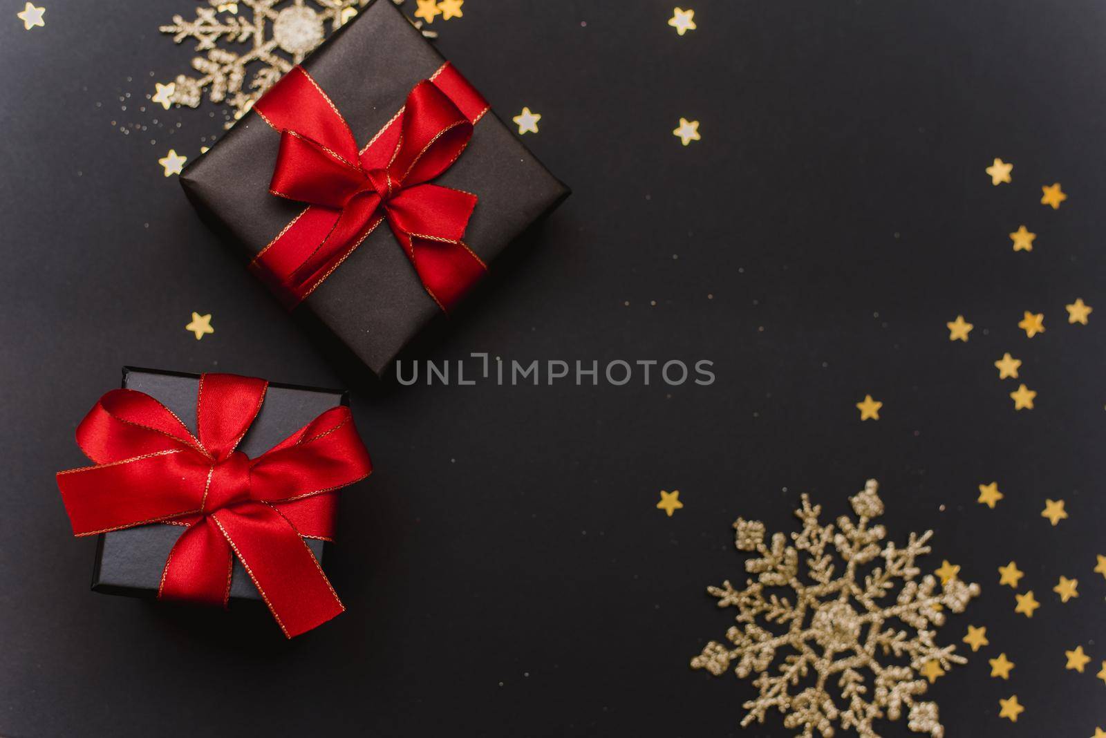 Beautiful Christmas golden snowflakes with gifts on a dark black background. Flat lay. Copy space. by etonastenka