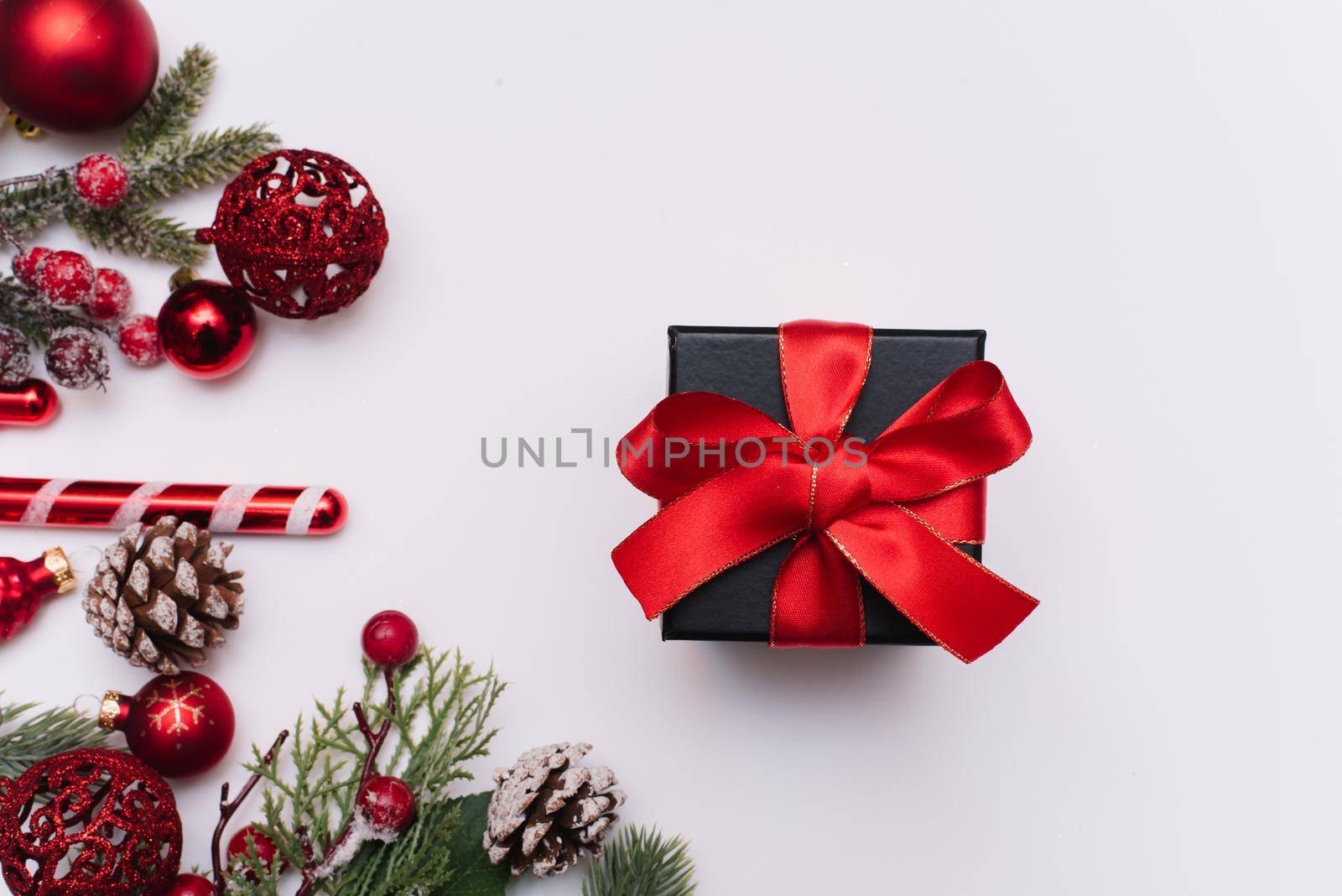 Christmas gift with a red bow on a white background with fir branches and decorations on a white background. View from above by etonastenka