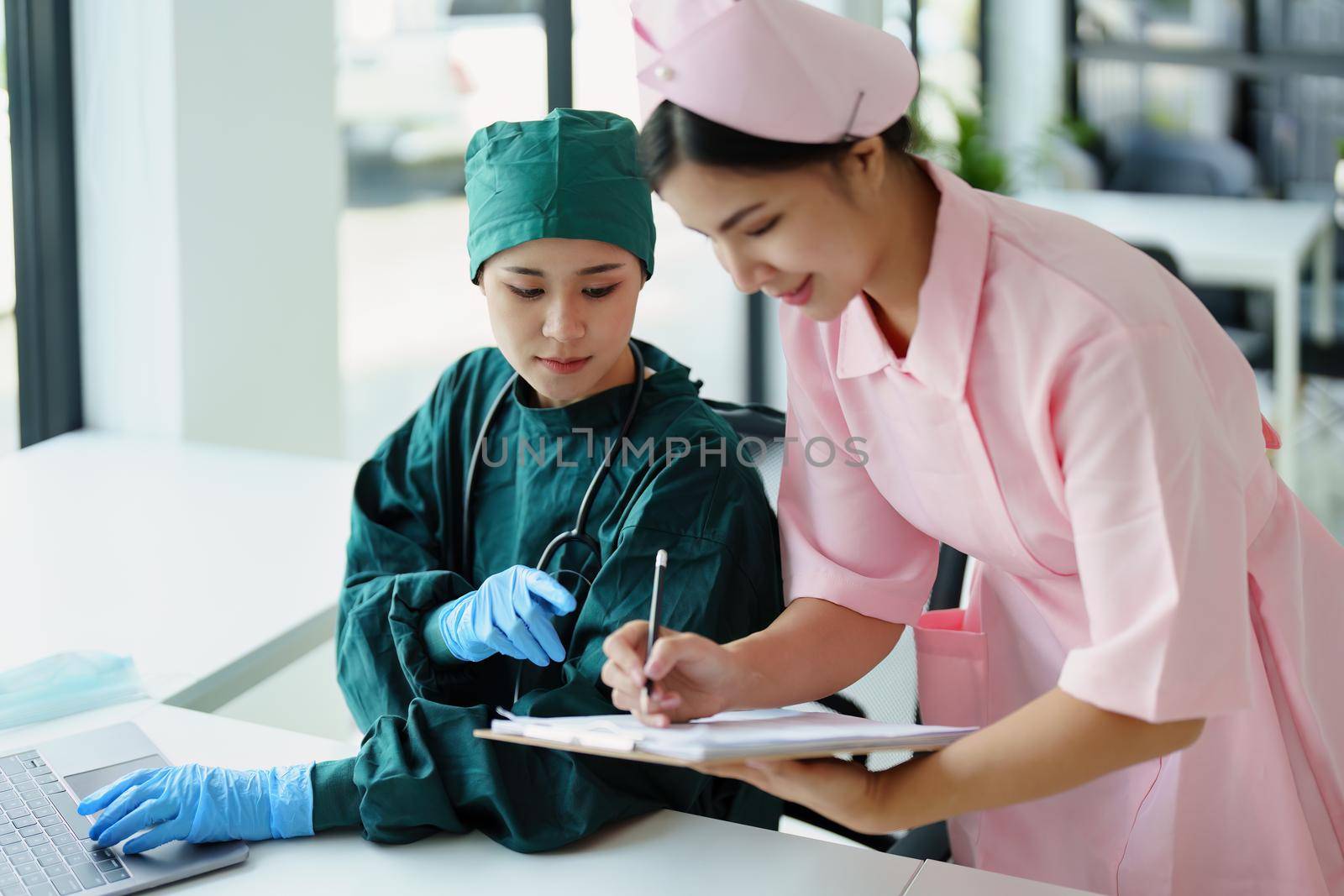 Portrait of Asian doctors and nurses using computers and documents to view patient information to analyze symptoms before treatment