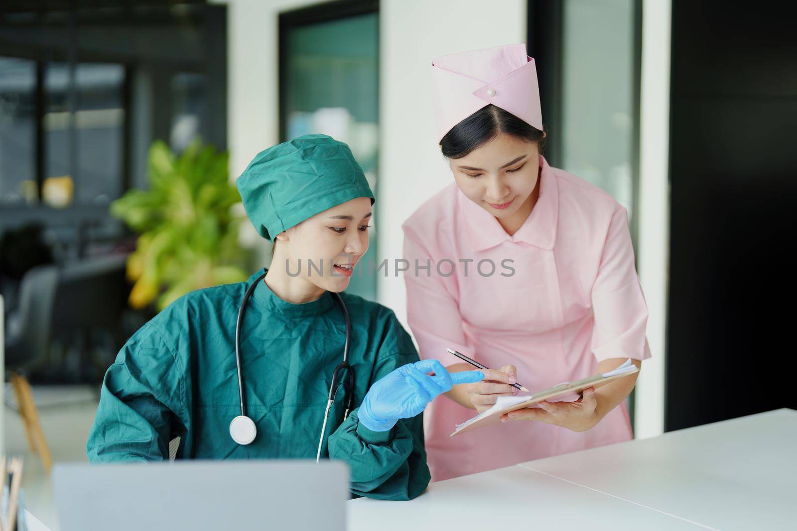 Portrait of Asian doctors and nurses using computers and documents to view patient information to analyze symptoms before treatment