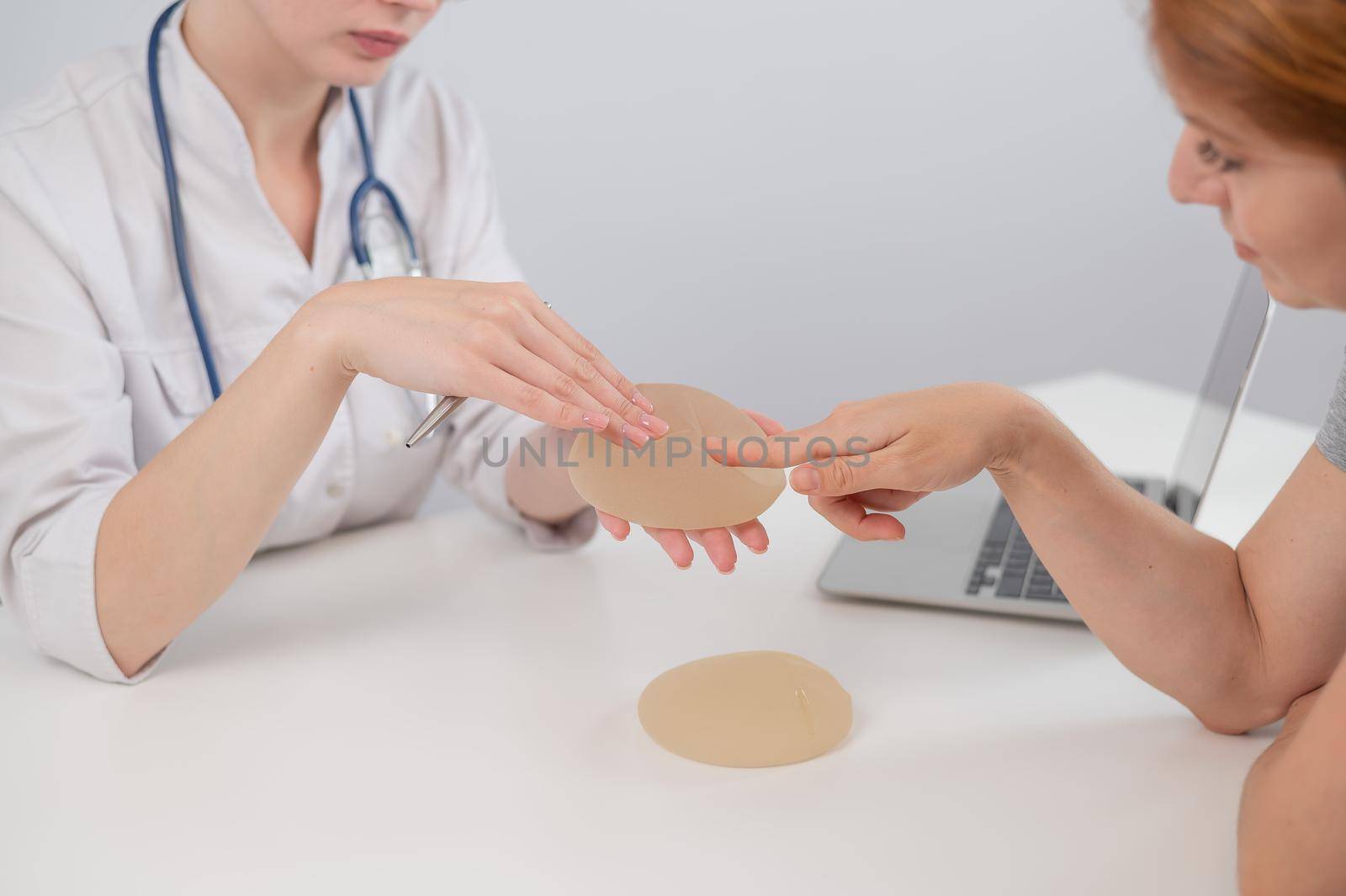 Caucasian woman and plastic surgeon choosing breast implants. by mrwed54