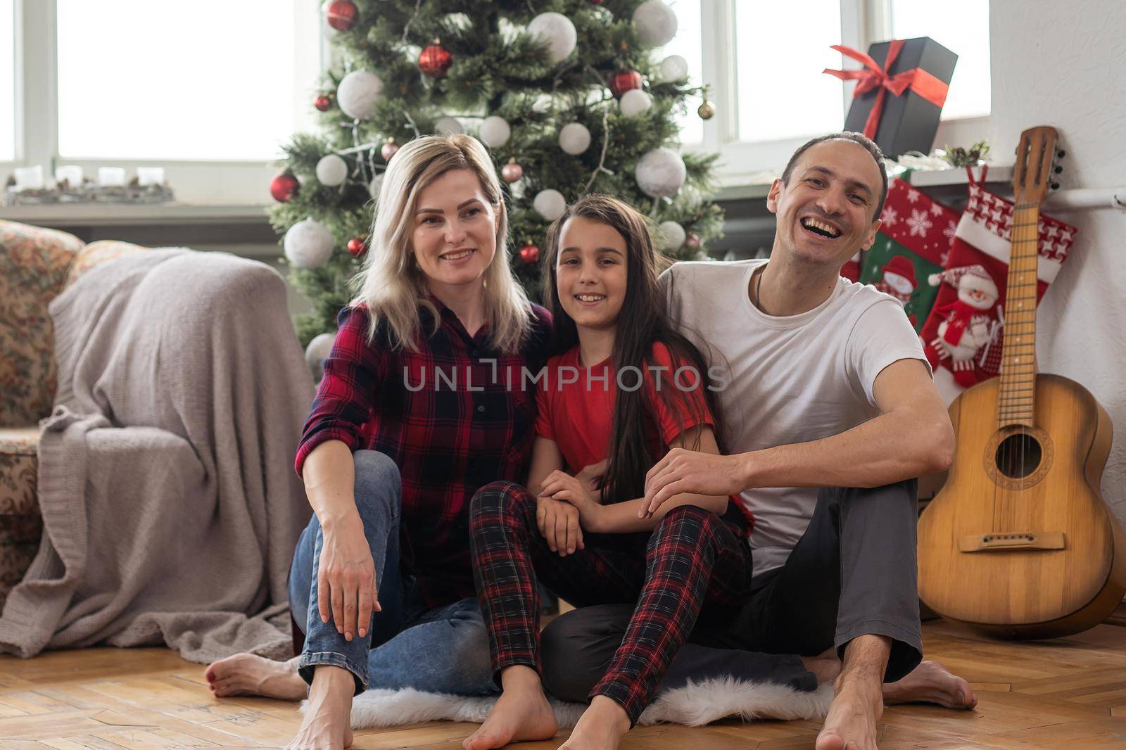 Young happy family while celebrating Christmas at home. by Andelov13