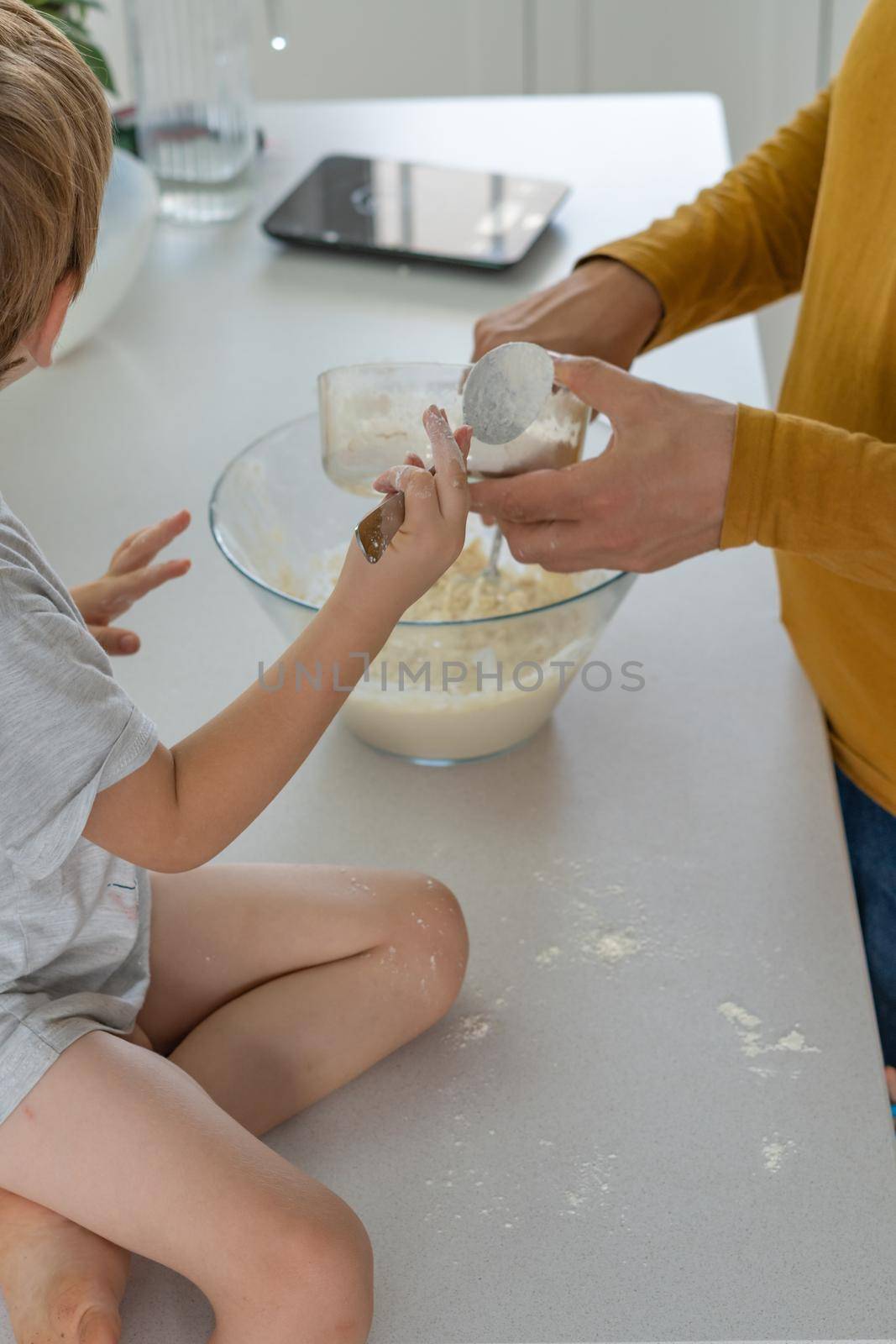 young man making homemade bread with his son in his home kitchen