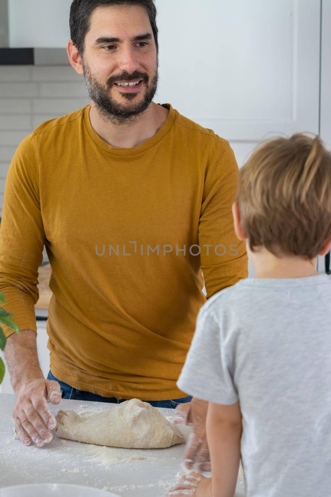 young man making homemade bread with his son in his home kitchen