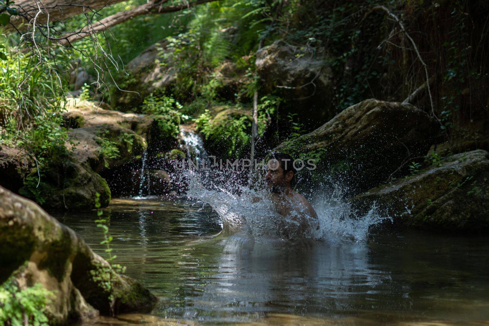 young man jumping from a rock into the river by joseantona