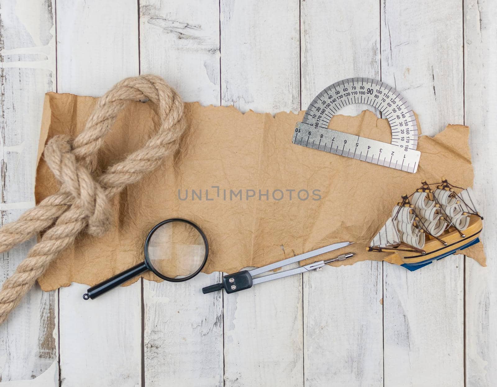 old paper, rope, magnifying glass and model classic boat on wood background  by inxti