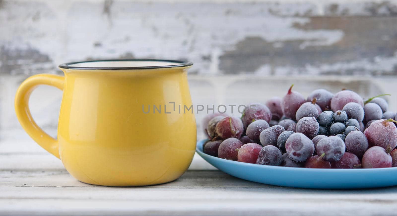 Frozen berries fruits background in ceramic plate close up.Fruits with frost. on vintage white wooden planks, blank space for text, copy space