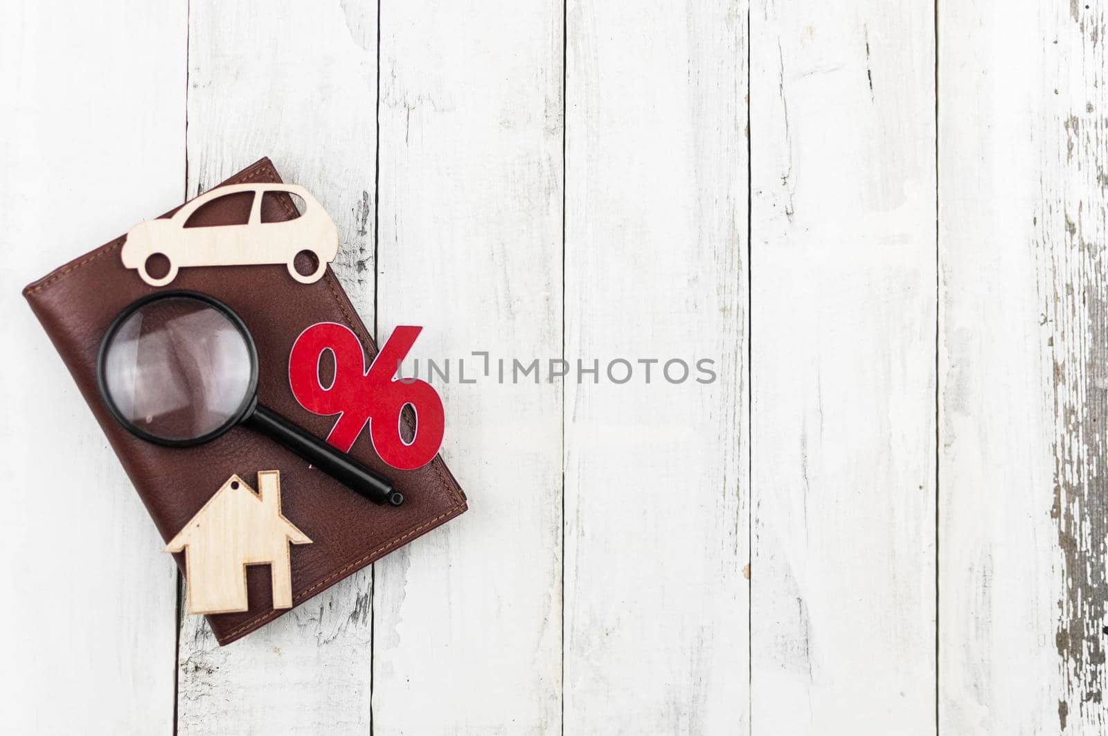 brown leather wallet with little model house and car on wood board background