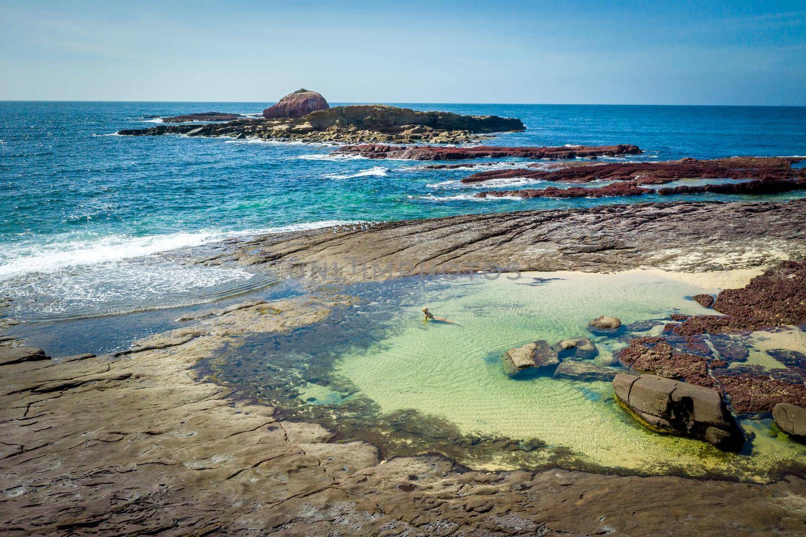 Female in bikini swimming and  relaxing in ocean rockpools by lovleah