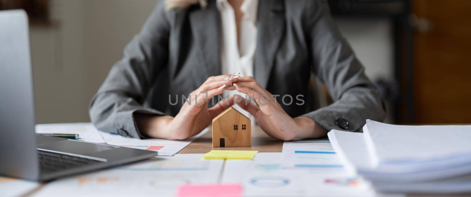 Female hands saving small house with a roof. Home insurance concept.