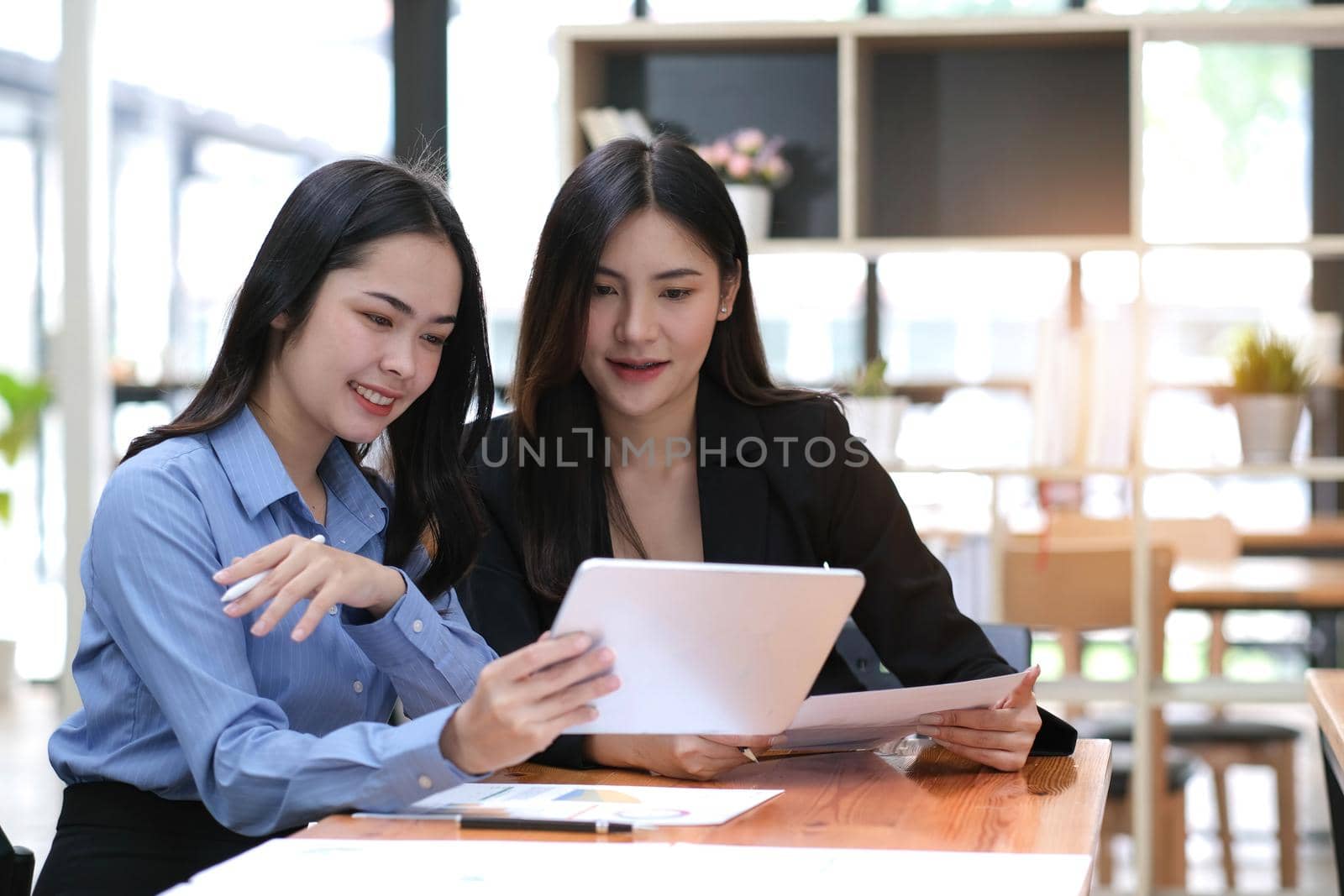 Two businesswoman meeting and working together on tablet in office. by wichayada