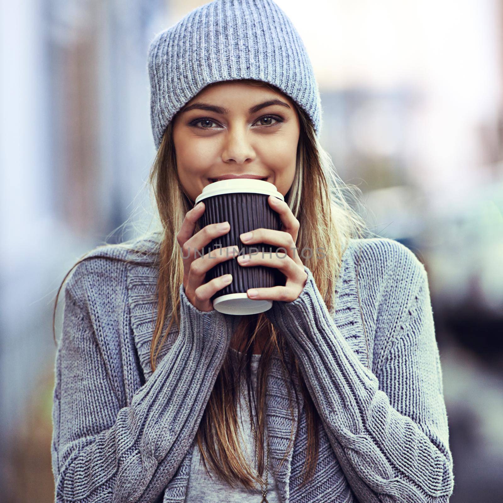 Shes just been to her favorite coffee place. Portrait of a beautful young woman drinking coffee while out in the city