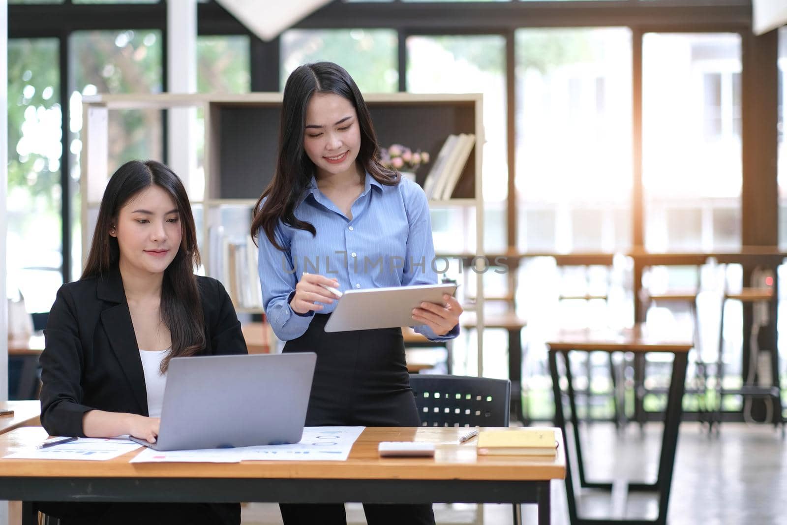 Two Young Asian businesswoman discuss with new startup project Idea presentation, analyze planning and financial statistics and investment market at office. by wichayada