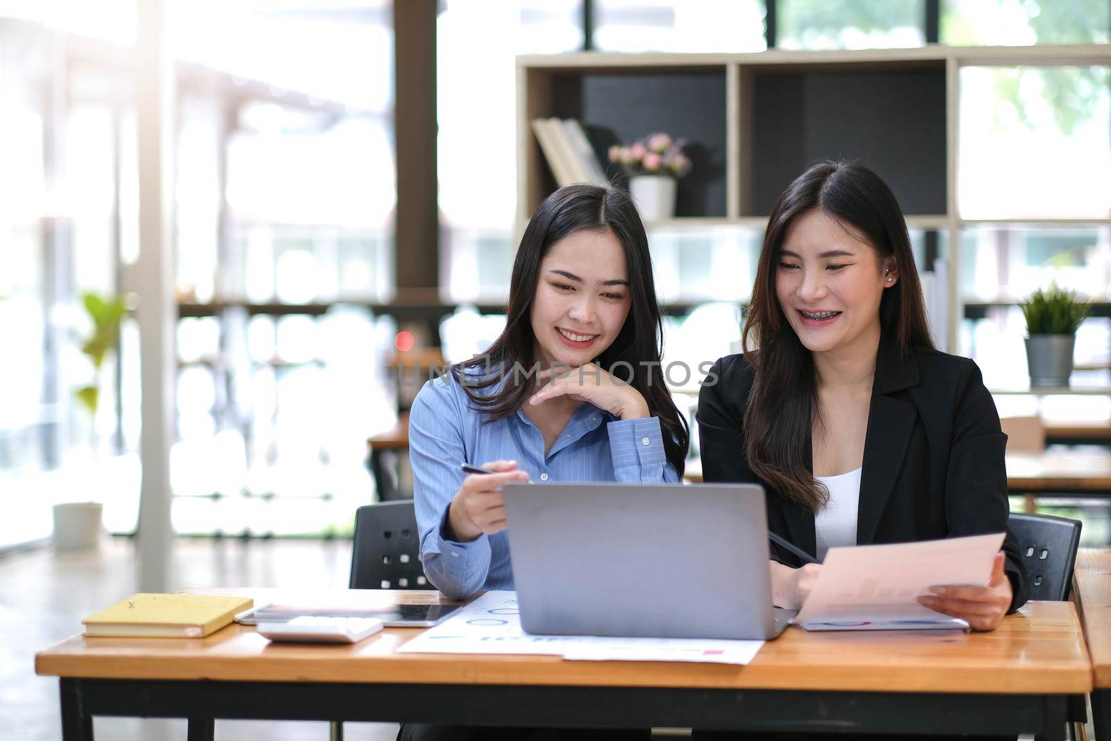 Two Young Asian businesswoman discuss with new startup project Idea presentation, analyze planning and financial statistics and investment market at office. by wichayada