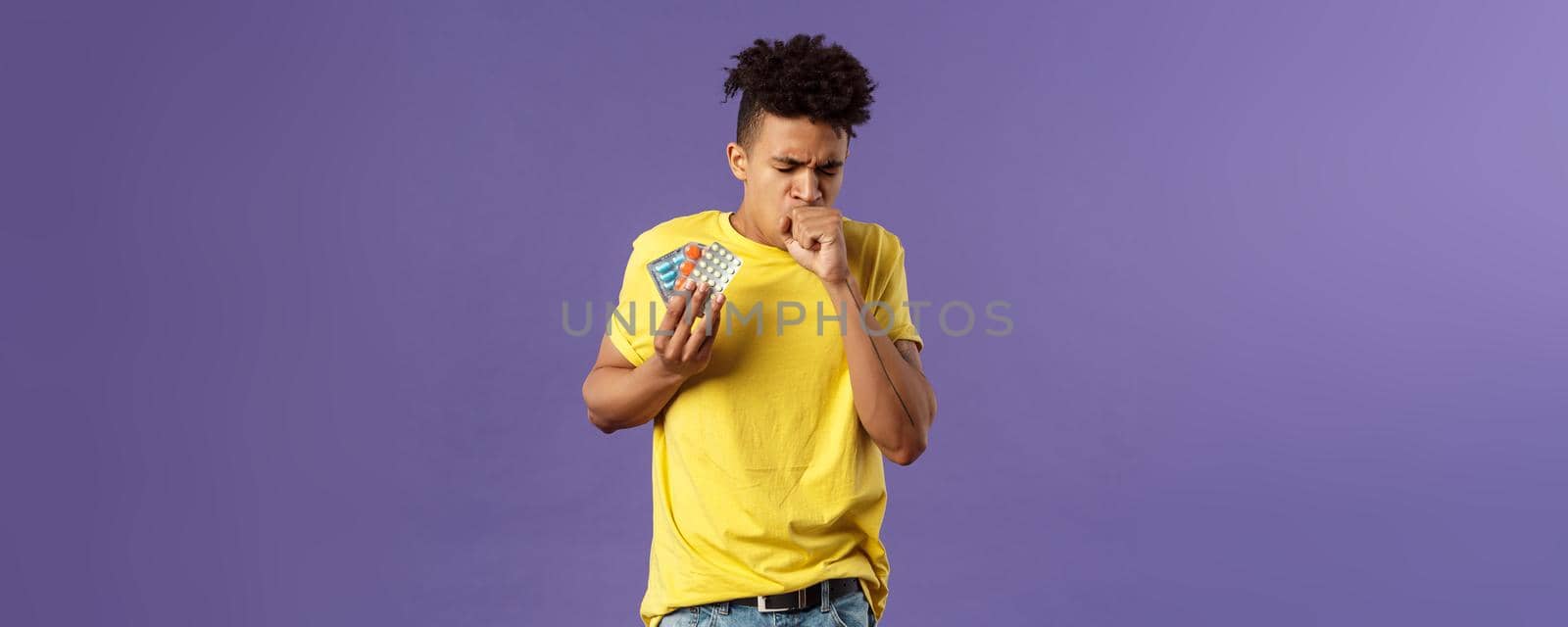 Health, influenza, covid-19 concept. Portrait of ill young man caught cold, have severe caugh, holding pills, showing drugs bought in drugstore, standing purple background feeling bad by Benzoix