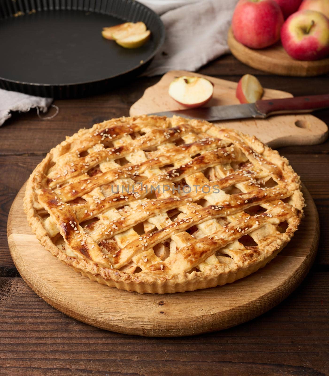 Round baked apple pie on a brown wooden table, top view