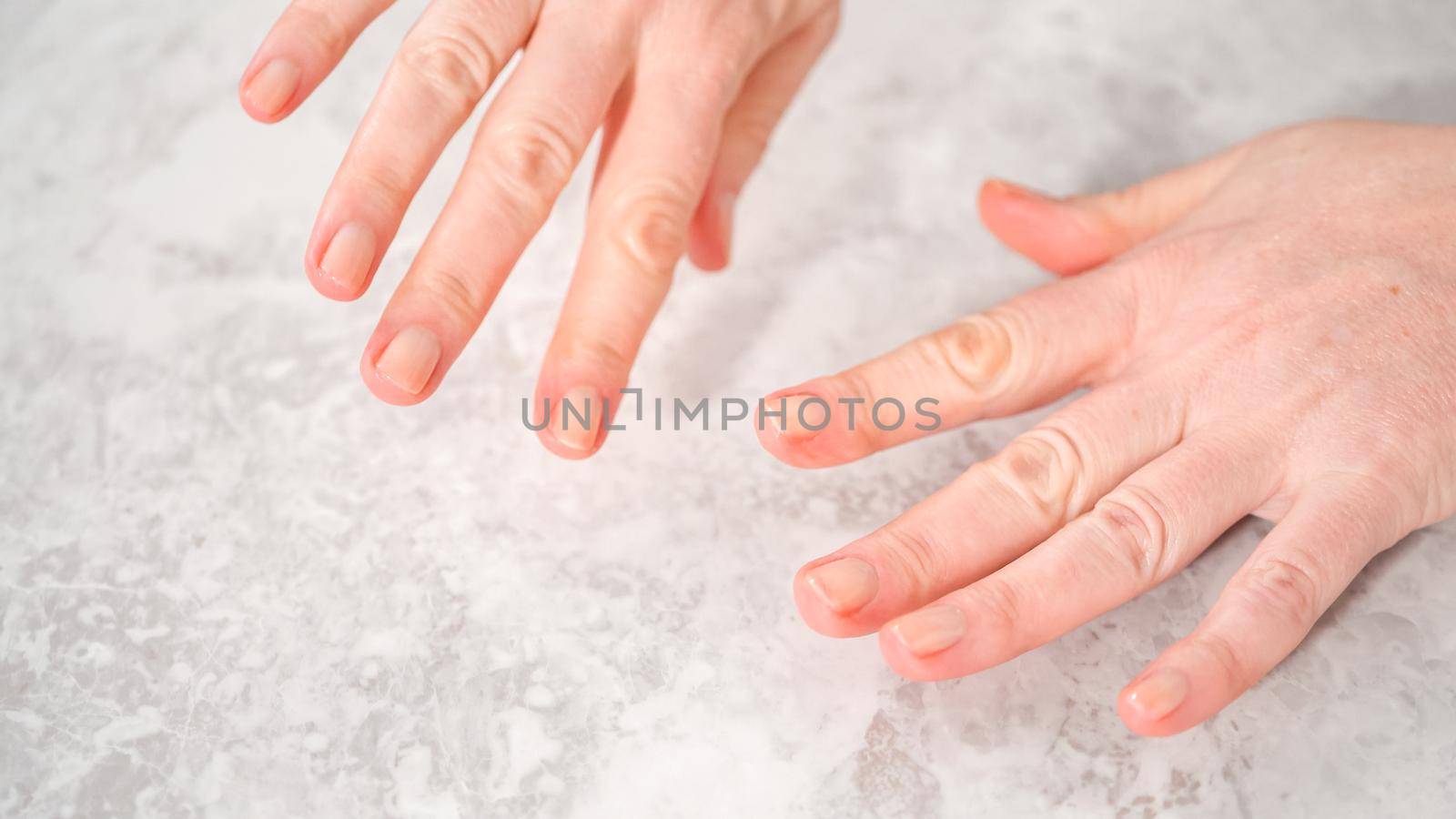 Woman finishing her manicure at home with simple manicure tools. Painting nails with fresh nail polish.