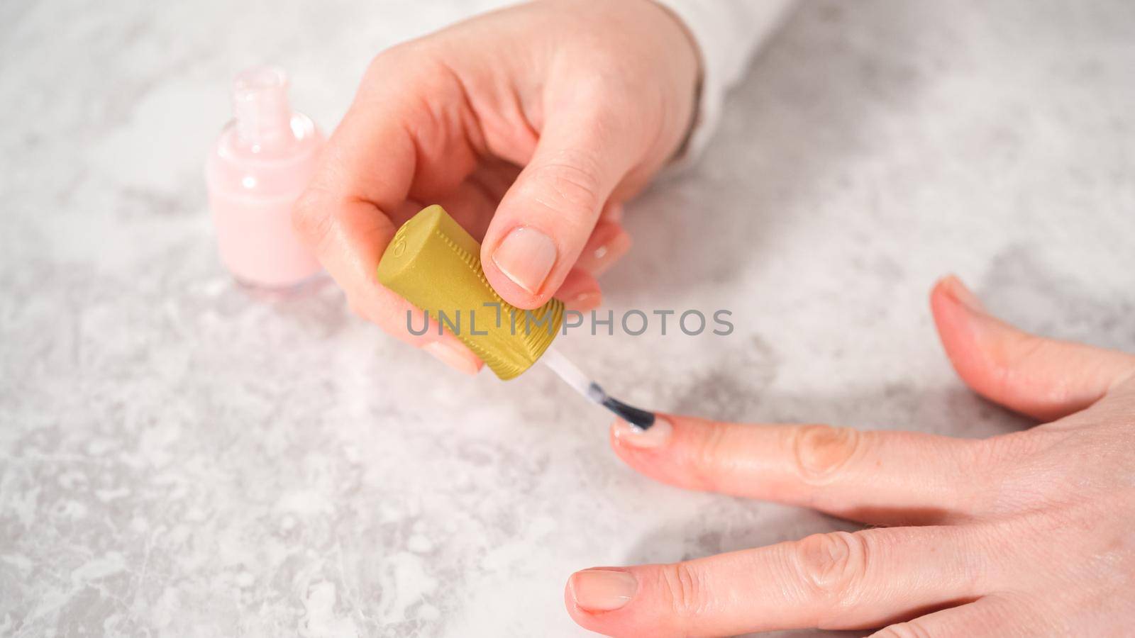 Woman finishing her manicure at home with simple manicure tools. Painting nails with fresh nail polish.