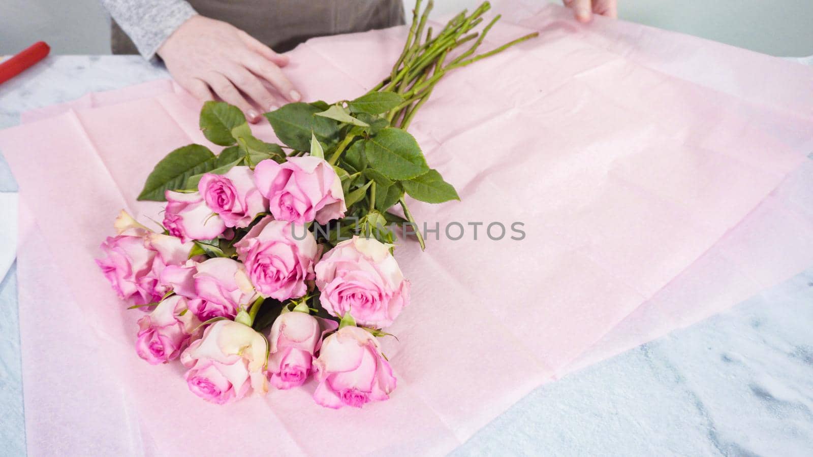 Step by step. Florist arranging a bouquet from pink roses.