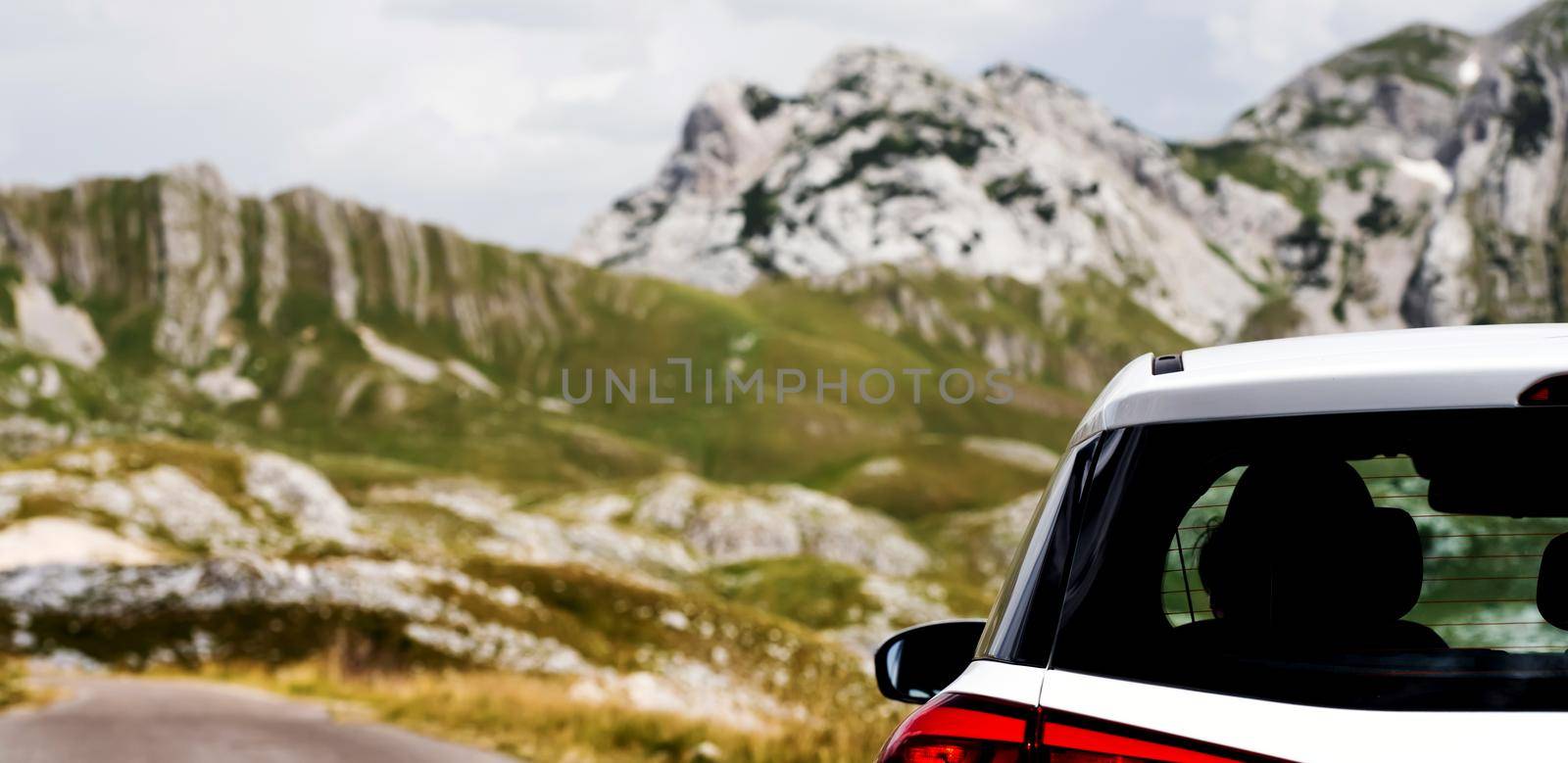 White car with the scenic mountains view on background. Vehicle in beautiful landscape of national park in sunny day