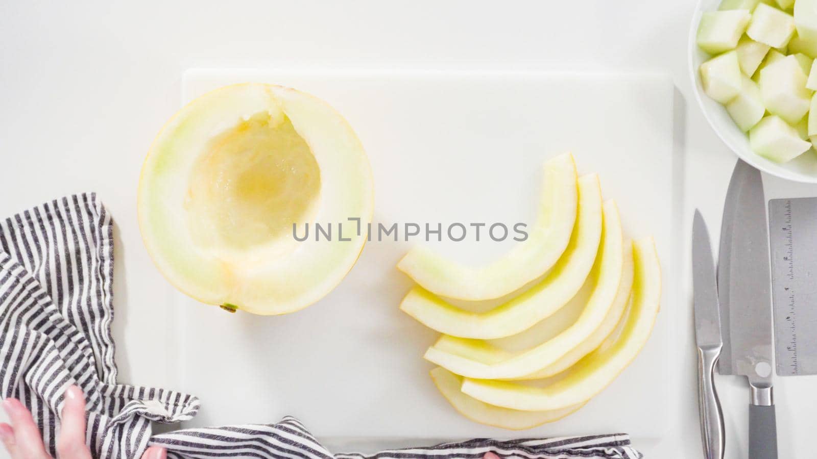 Step by step. Flat lay. Slicong golden dewlicious melon on a white cutting board.