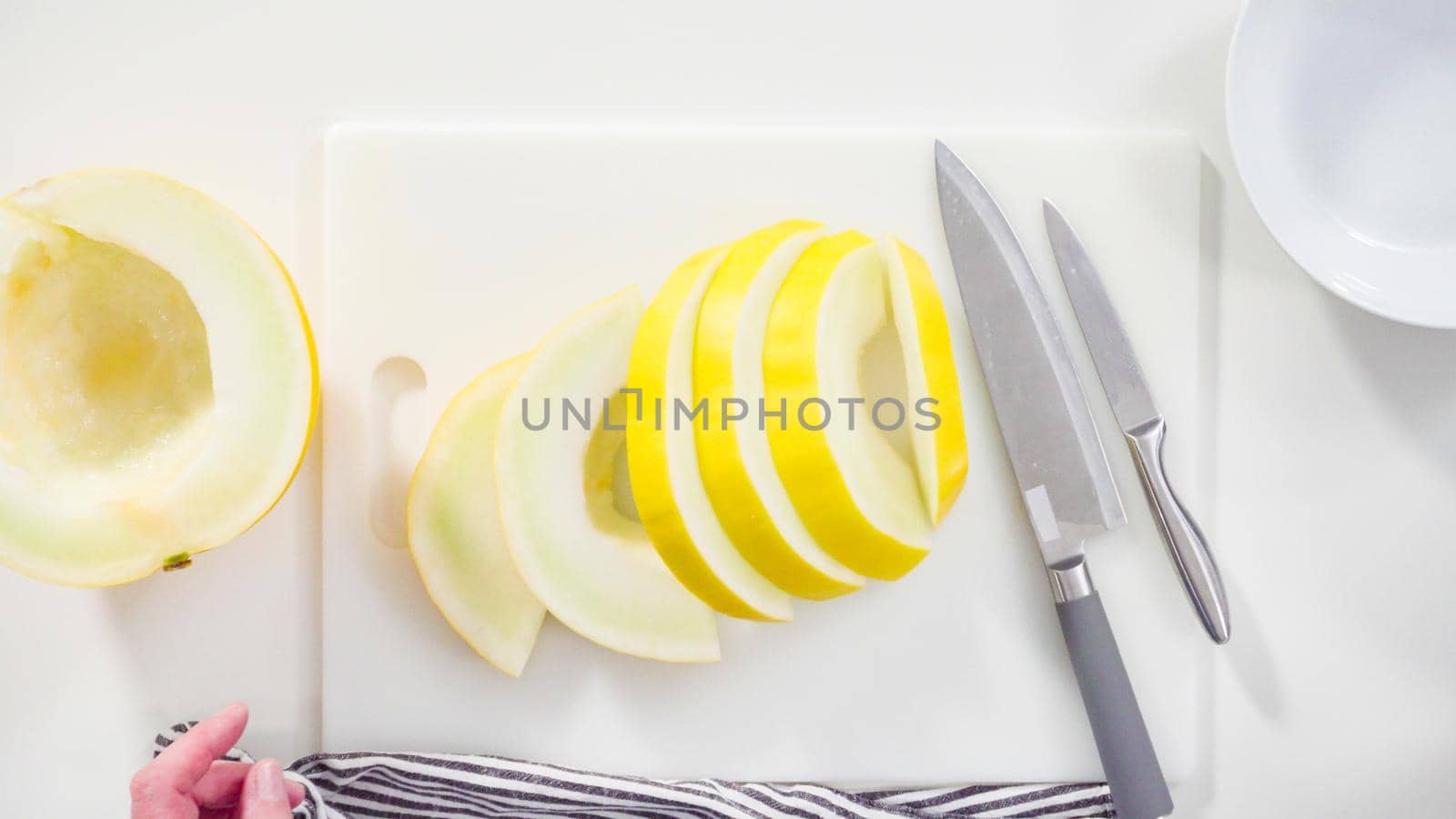 Step by step. Flat lay. Slicong golden dewlicious melon on a white cutting board.