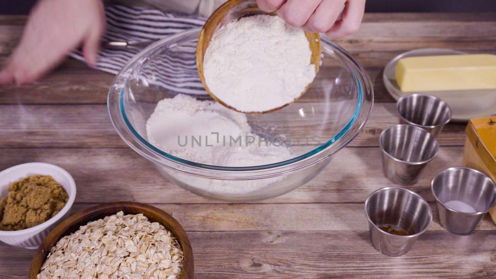 Step by step. Mixing ingredients to bake oatmeal raising cookies in a glass mixing bowl.