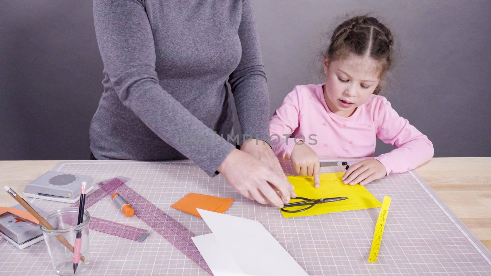 Little girl making a handmade Father's Day card from construction paper.