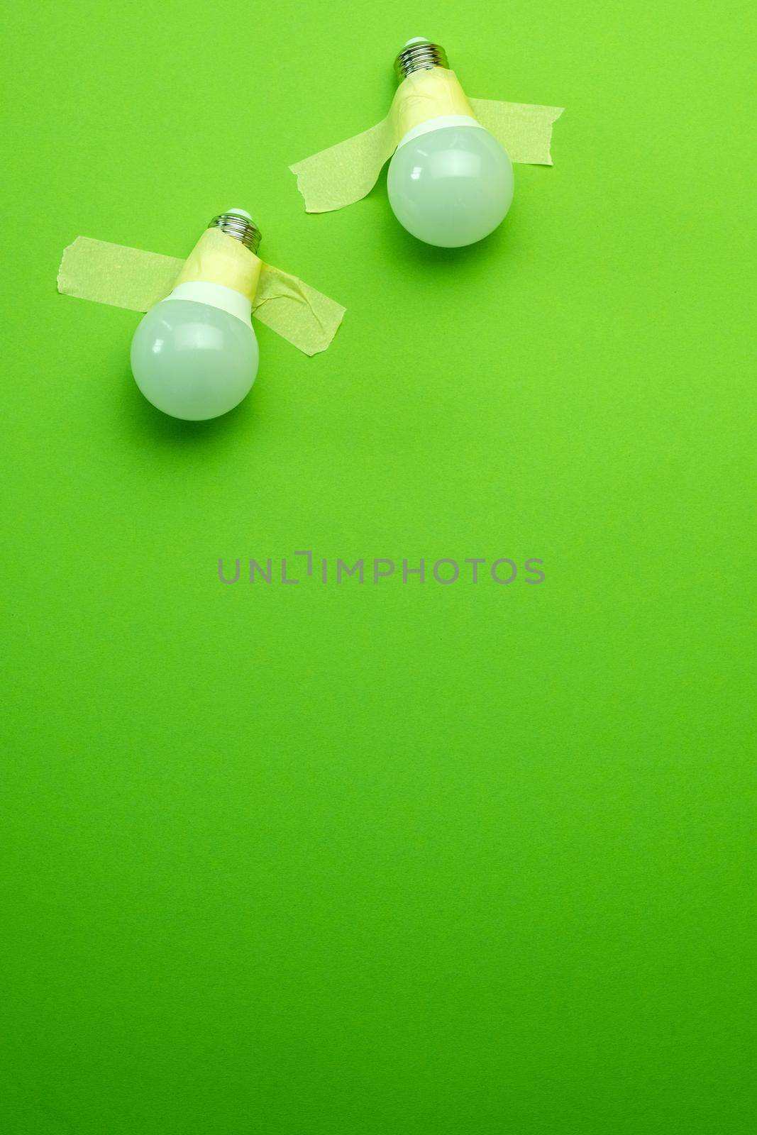 Two lamps lightbulb attached with tape on green background. Concept of creativity and team inspiration