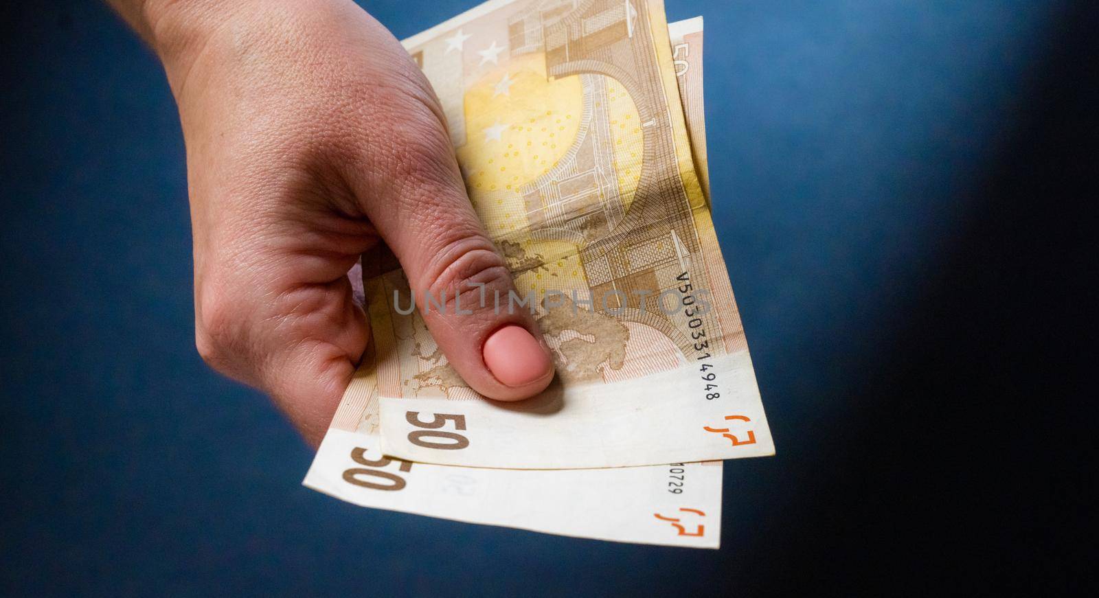 Hand holding fifty euro banknotes. European currency in cash and person with money closeup