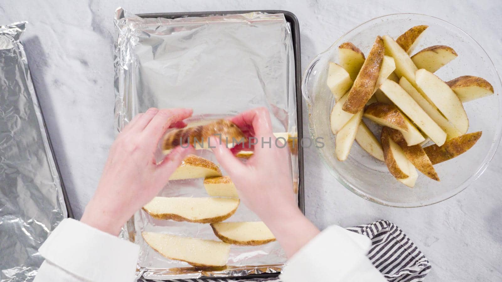 Flat lay. Step by step. Preparing russet potatoes in wedges with olive oil and spices to bake in the oven.