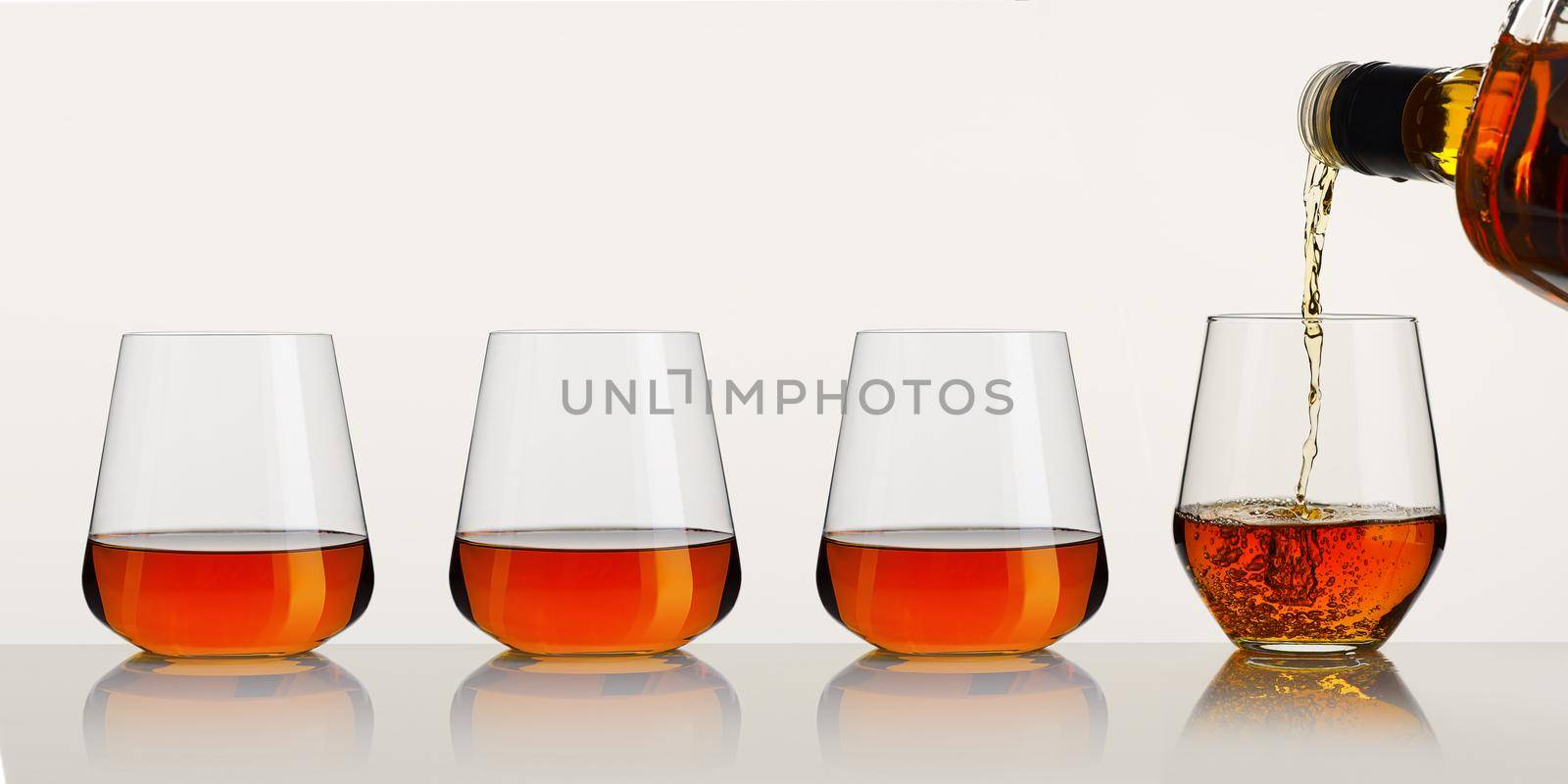 whiskey or brandy being poured into a glass from bottle on white background. Pouring whisky from a bottle by PhotoTime