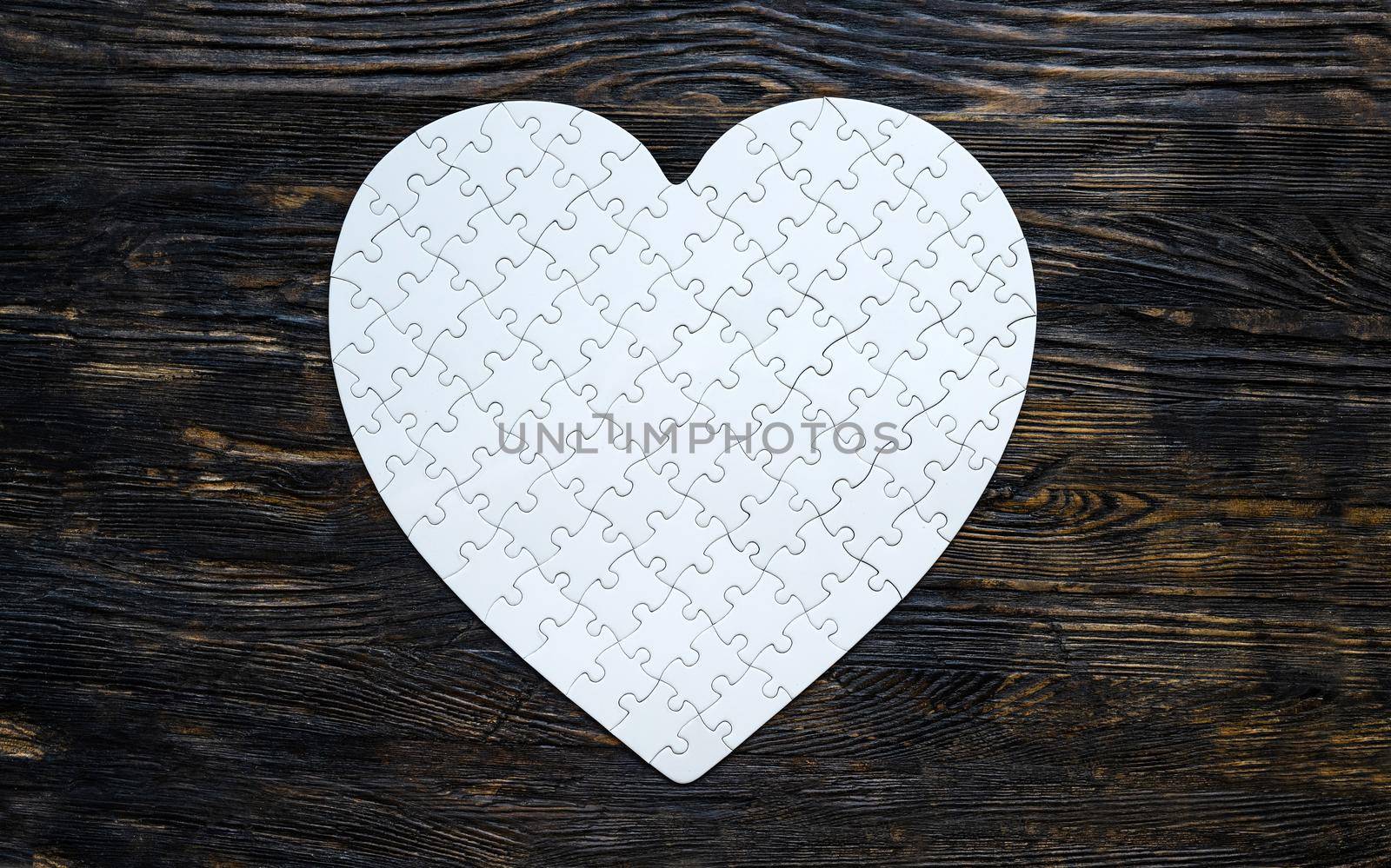 White heart shape puzzle on black table as symbol of love, romantic and feelings.
