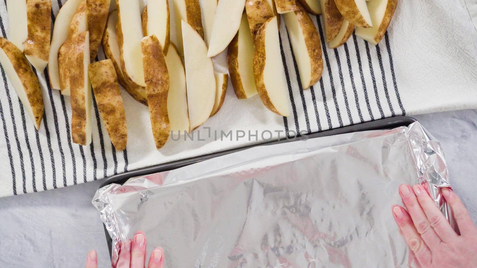 Flat lay. Step by step. Preparing russet potatoes in wedges with olive oil and spices to bake in the oven.