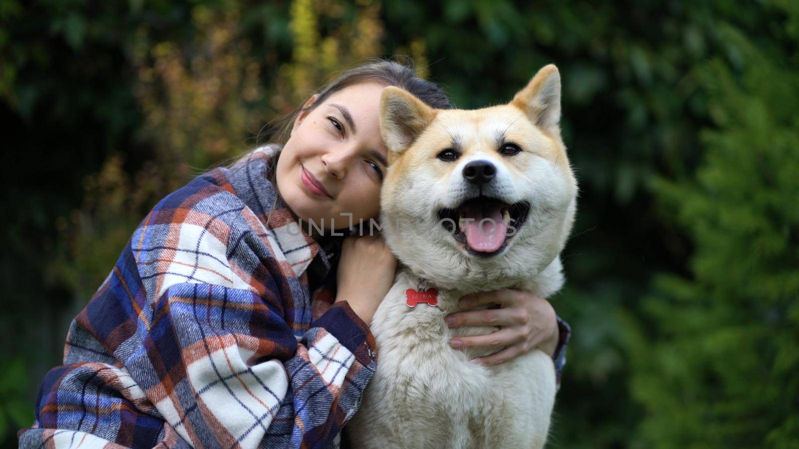 The girl hugs the dog and puts her head on her and look at the camera.