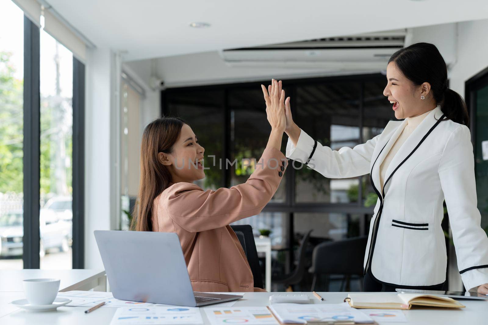 businesswomen giving hi five touching hands and thumb up during meeting for celebration business achievement and success with teamwork.