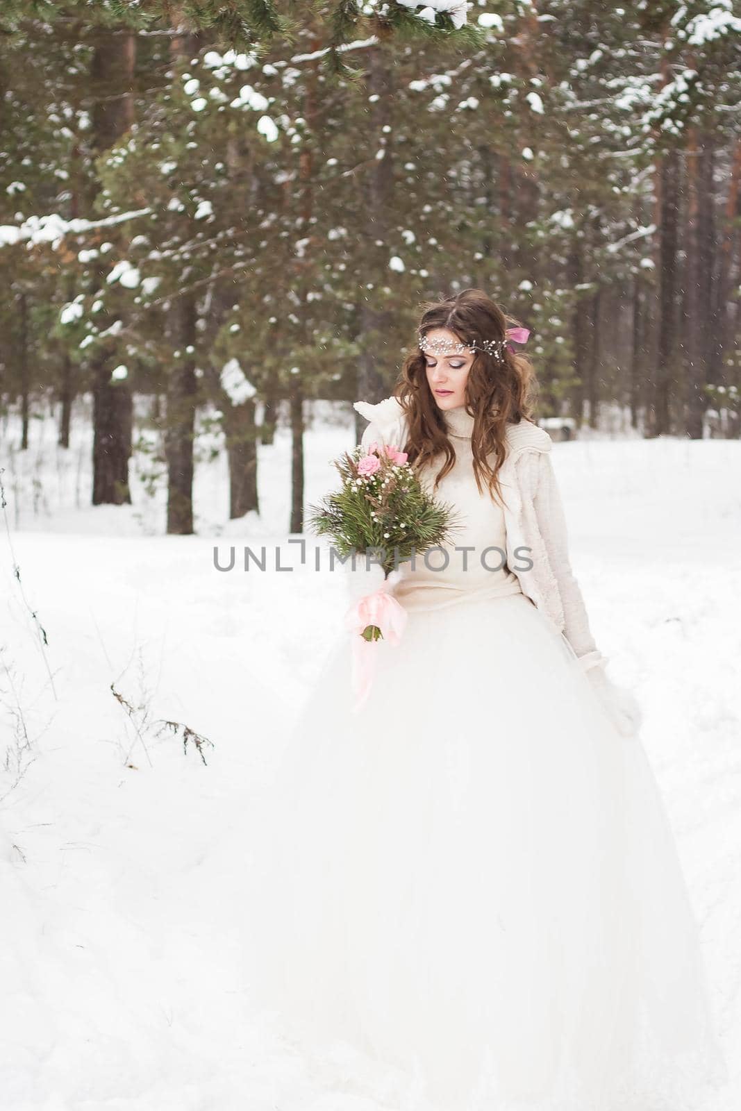 Beautiful bride in a white dress with a bouquet in a snow-covered winter forest. Portrait of the bride in nature by Annu1tochka