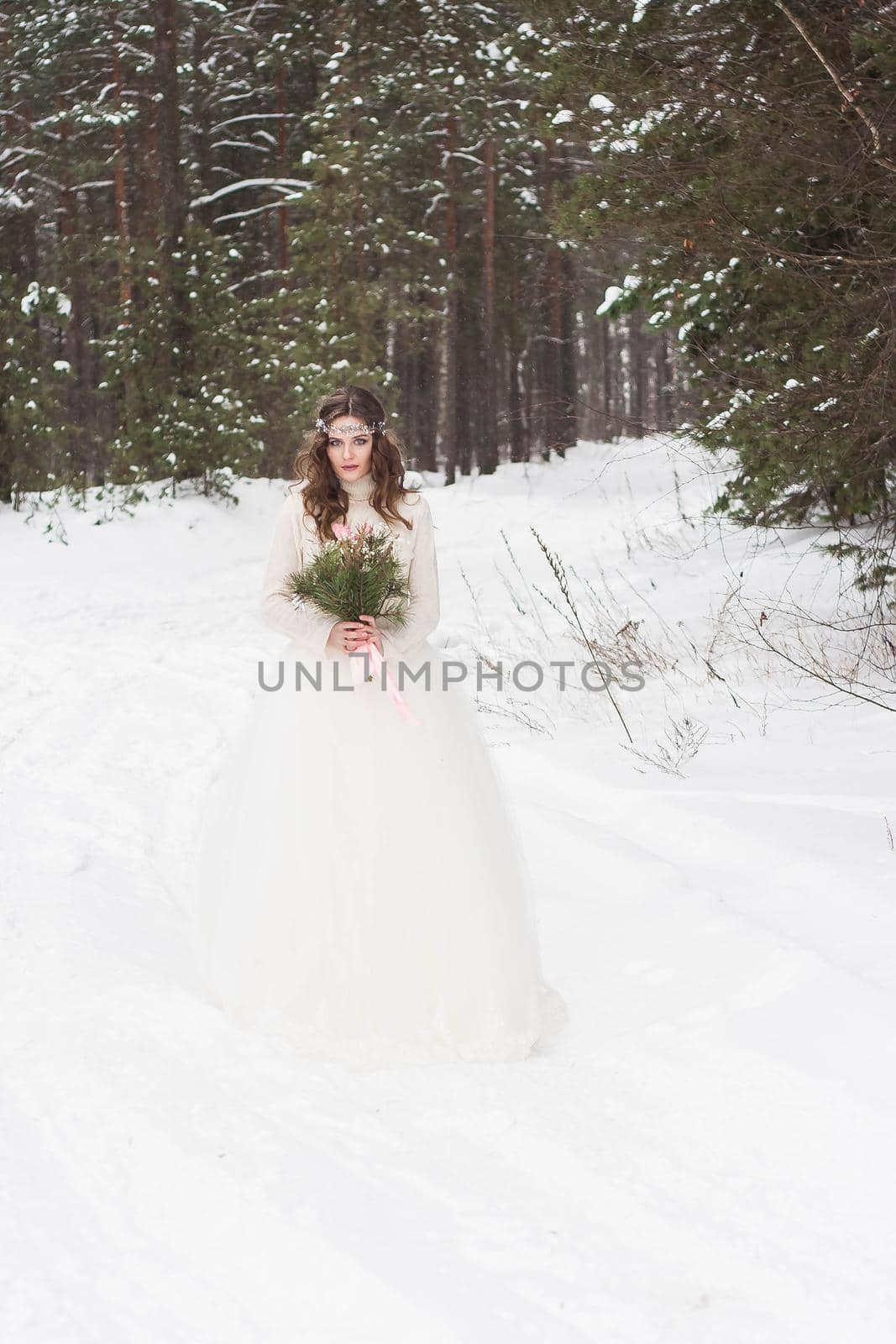 Beautiful bride in a white dress with a bouquet in a snow-covered winter forest. Portrait of the bride in nature by Annu1tochka