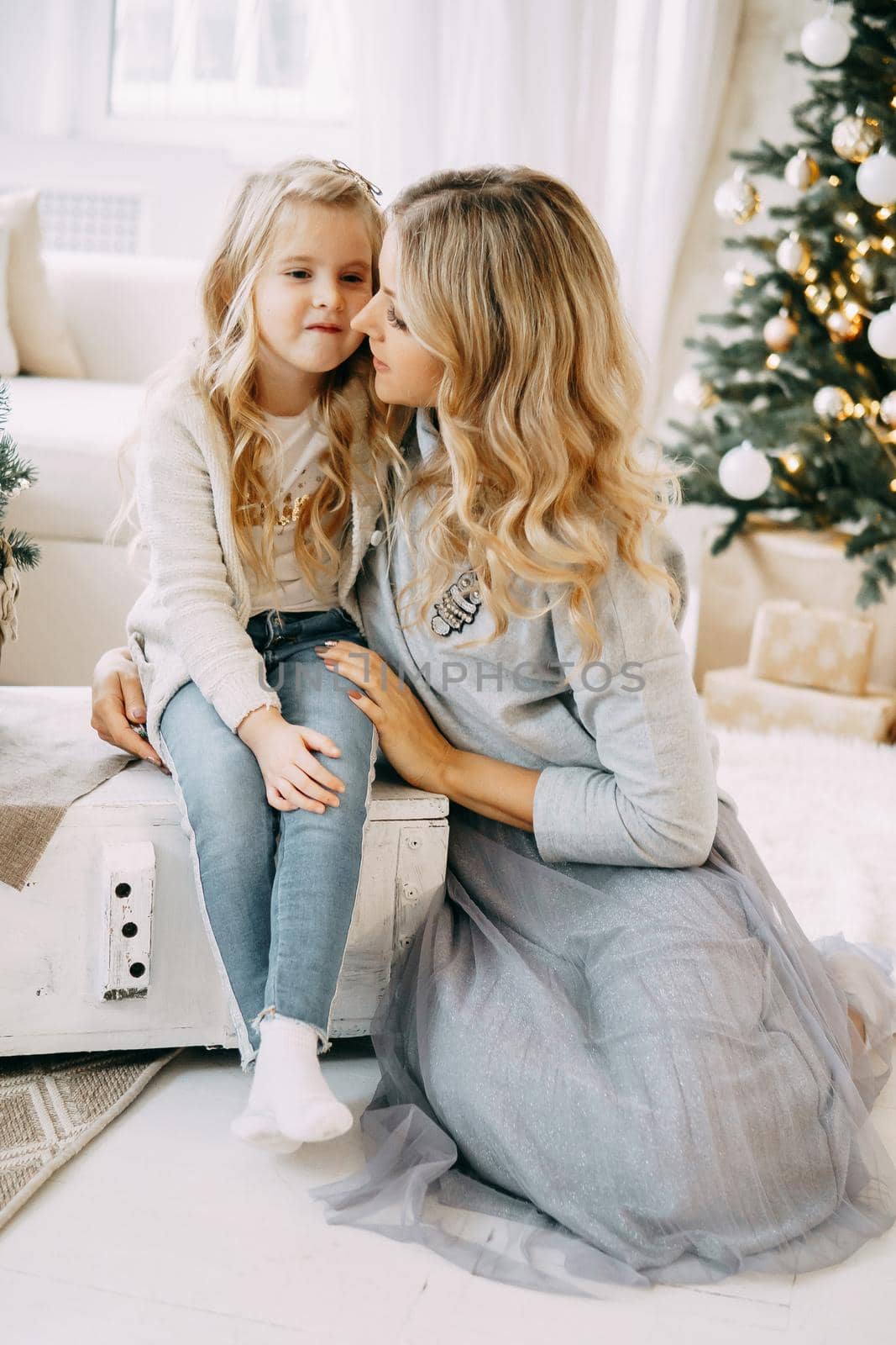 Happy family: mother and daughter. Family in a bright New Year's interior with a Christmas tree.