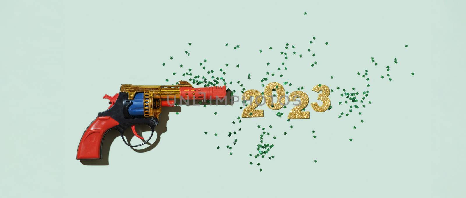 Creative composition with a toy gun and numbers of the new year 2023.