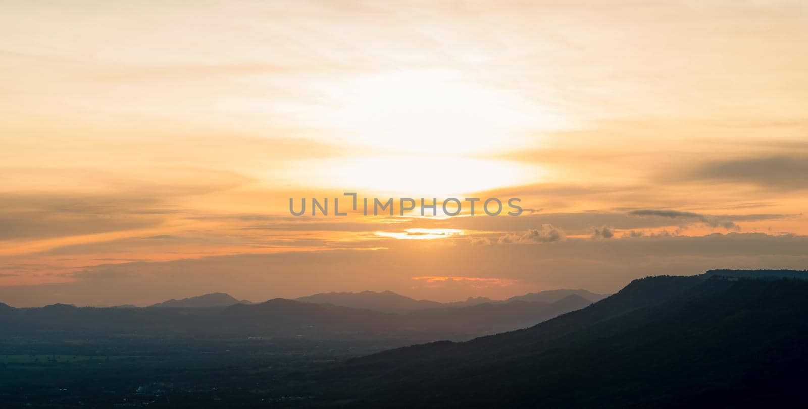 Landscape of mountain range with sunset sky. Mountain at dusk. Orange sky and clouds at sunset. Mountain valley. Mountain layer at dusk. Beauty in nature. Tranquility scene. Beautiful sunset sky.