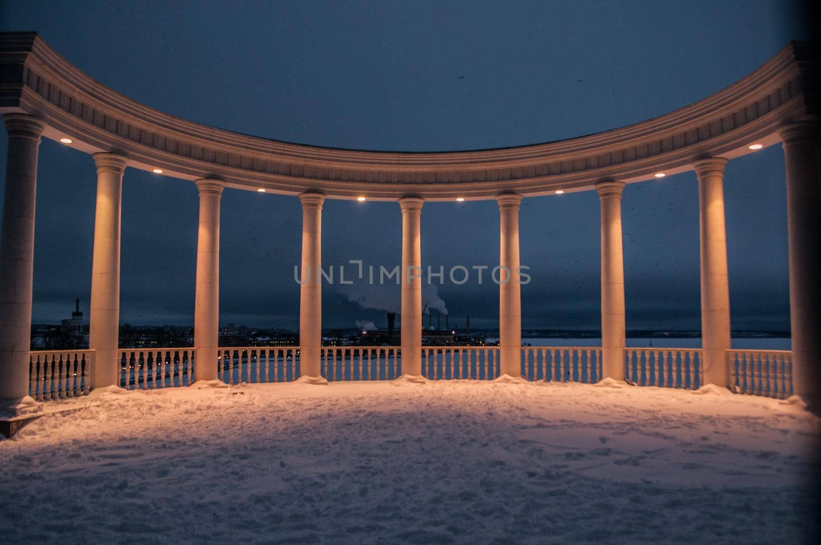 Beautiful white rotunda on the shore of the pond in the evening.