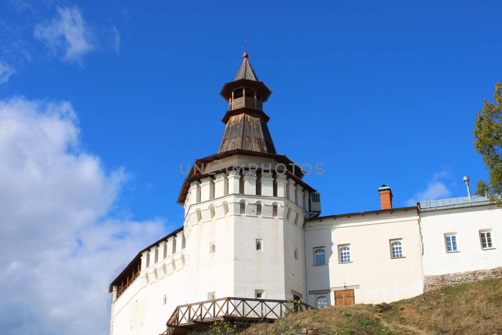 An old white church standing on a cliff against a blue sky.